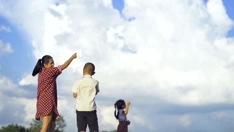 asian families, mothers, sons and daughters are playing kites on a happy holiday.