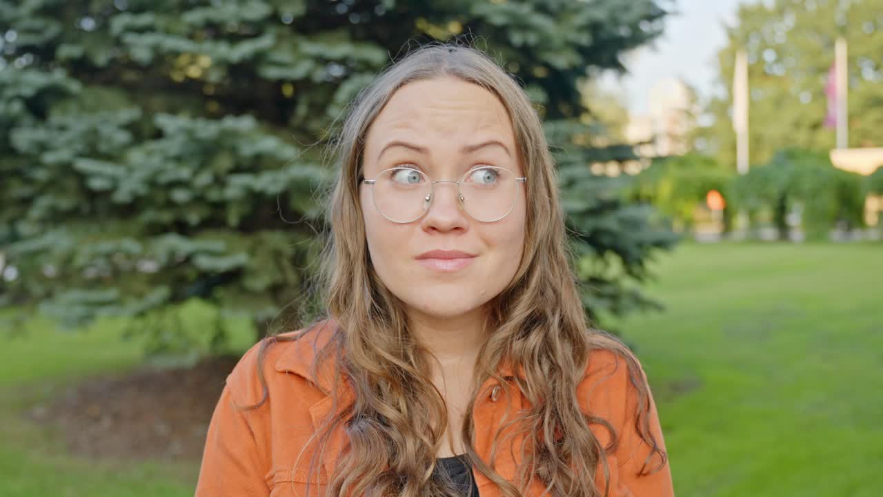 Woman smirks looking confused and flirty scrunching eyebrows to puckered kissing lips