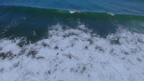 Two-surfers-going-under-a-wave-crashing-in-the-blue-ocean-in-Puerto-Rico-during-a-clear-day-with-blue-sky