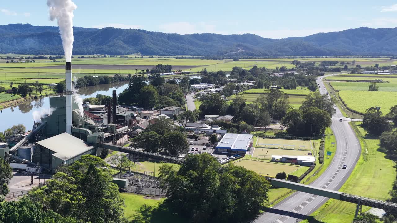 Aerial footage of a sugar mill in Murwillumbah, NSW, showcasing lush green fields and industrial structures under clear skies