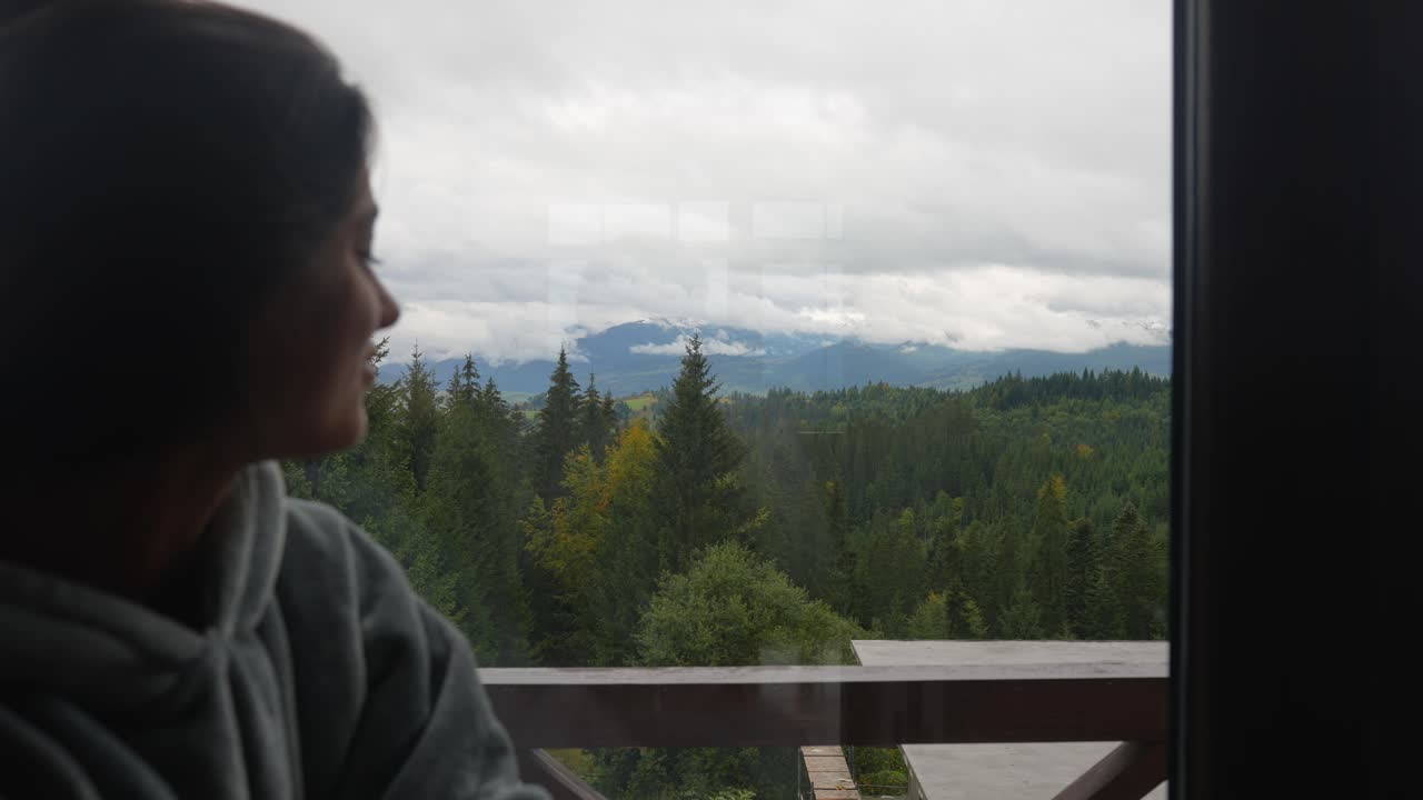 Woman looking at mountain view from window