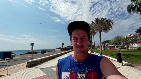 a self portrait shot of an adult male walking along a paved avenue by the coast