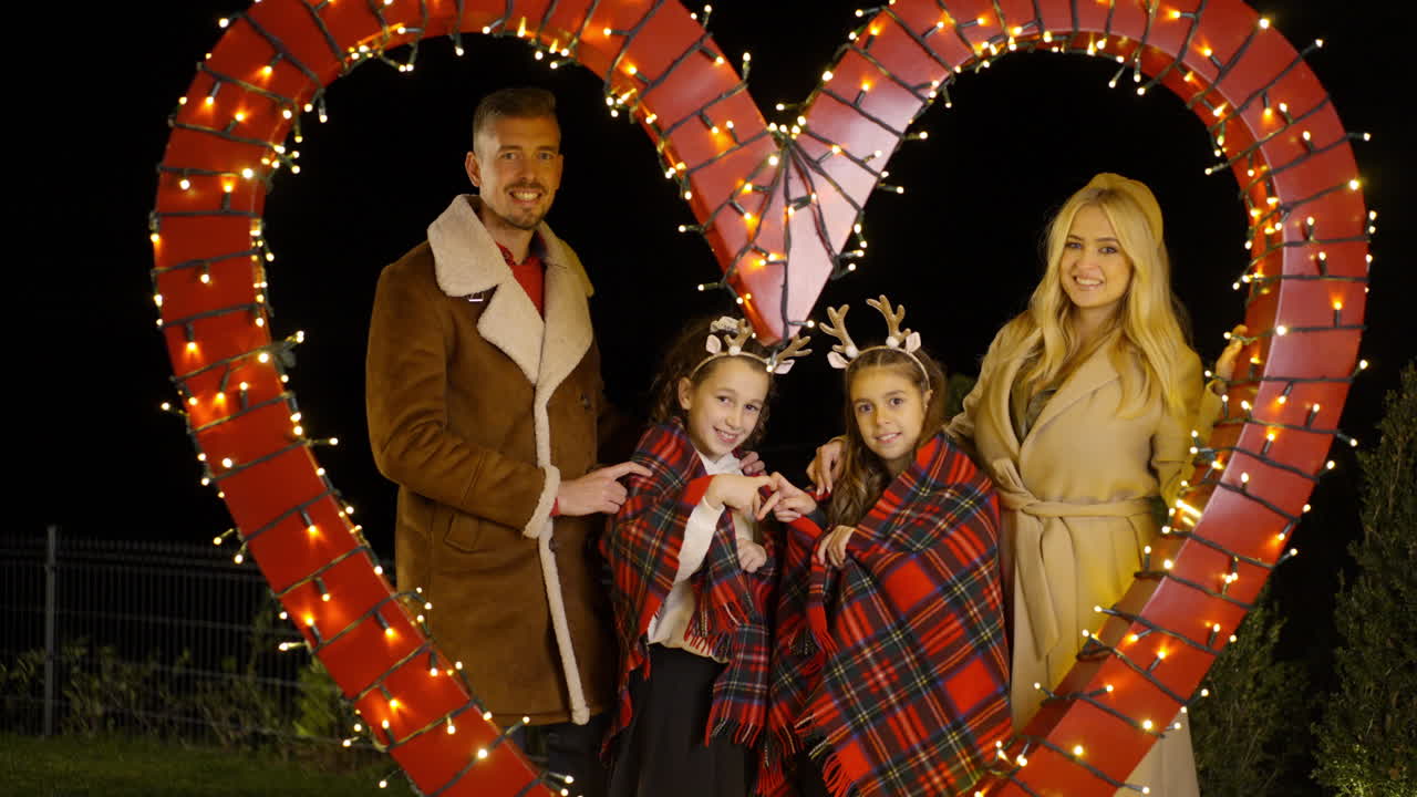 Family portrait in front of a heart with Christmas lights