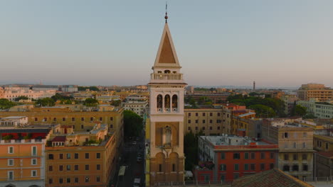 Fliegen-Sie-Um-Den-Schönen-Turm-Herum,-Die-Morgendliche-Stadt-Im-Hintergrund.-Kreisförmige-Luftaufnahme-Von-Gebäuden-Im-Stadtbezirk.-Rom,-Italien