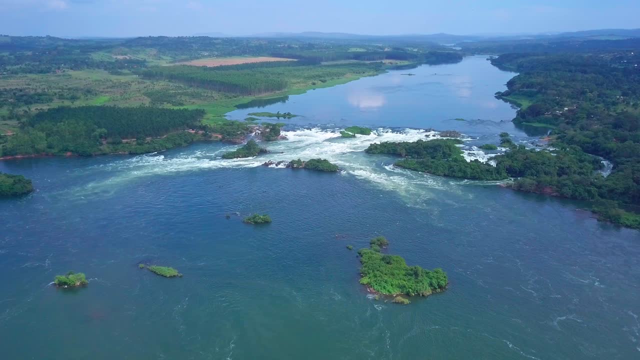 Aerial view capturing the River Nile in Uganda, Africa, with its powerful flow cascading over rocks, forming waterfalls and lush, picturesque islands