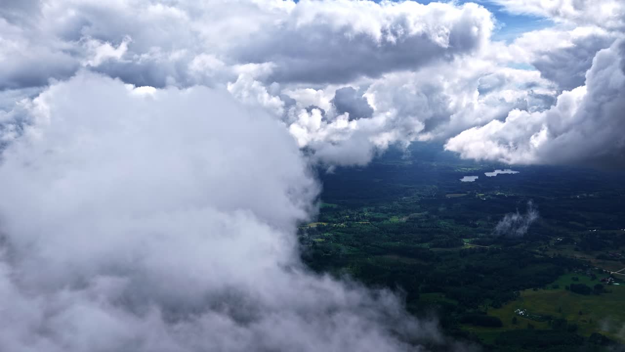 Drone fly through of clouds drifting over forested landscape in natural atmosphere