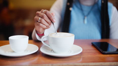 woman stirring coffee at cafe