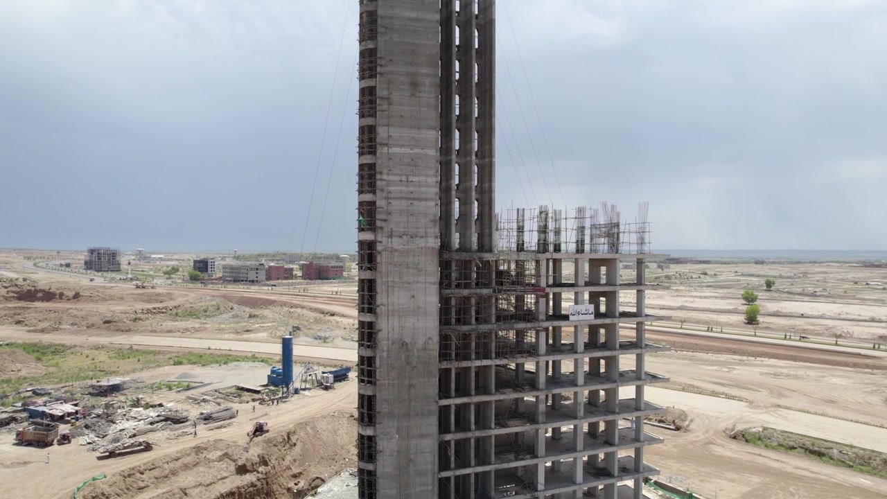 Concrete high rise structure under construction amid developing land at Capital Smart City, Pakistan