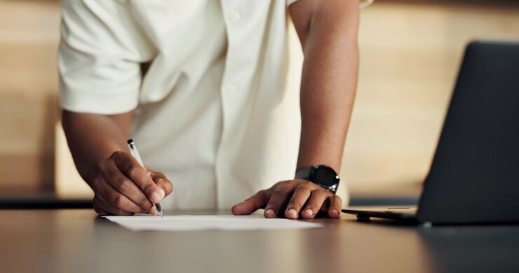 Person Signing Document on Desk in Modern Office