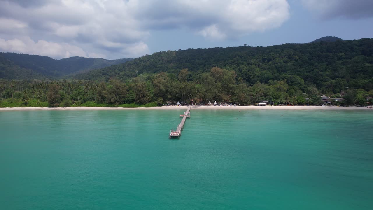 Spiaggia di Ao Phrao con sabbia bianca, collina lussureggiante e molo in legno - Isola di Koh Kood, Thailandia. Ripresa panoramica con drone.