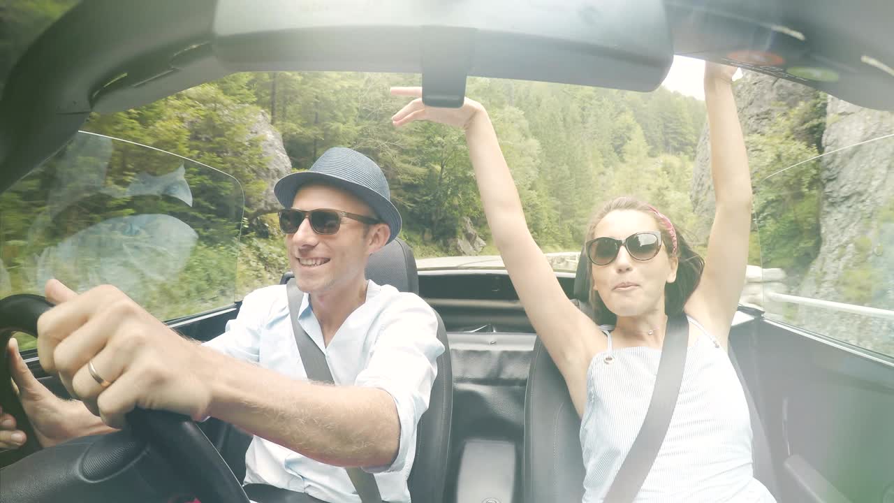 imágenes en 4k de una pareja en el descapotable cantando.