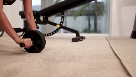 a woman performs an abdominal wheel workout in a well-lit home gym, focusing on core strength and stability