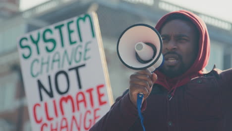 Männlicher-Demonstrant-Mit-Plakat-Und-Megafon-Auf-Demonstrationsmarsch-Gegen-Den-Klimawandel