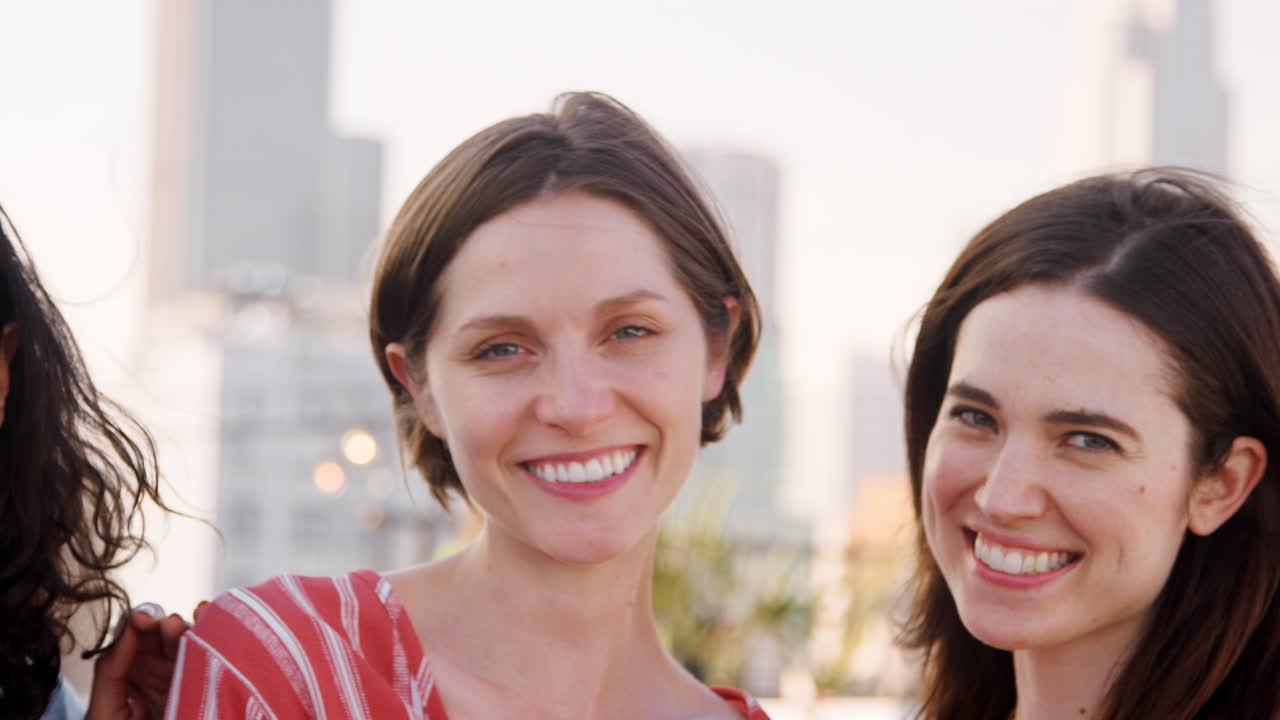 retrato de amigas reunidas en la terraza del techo para una fiesta con el horizonte de la ciudad en el fondo