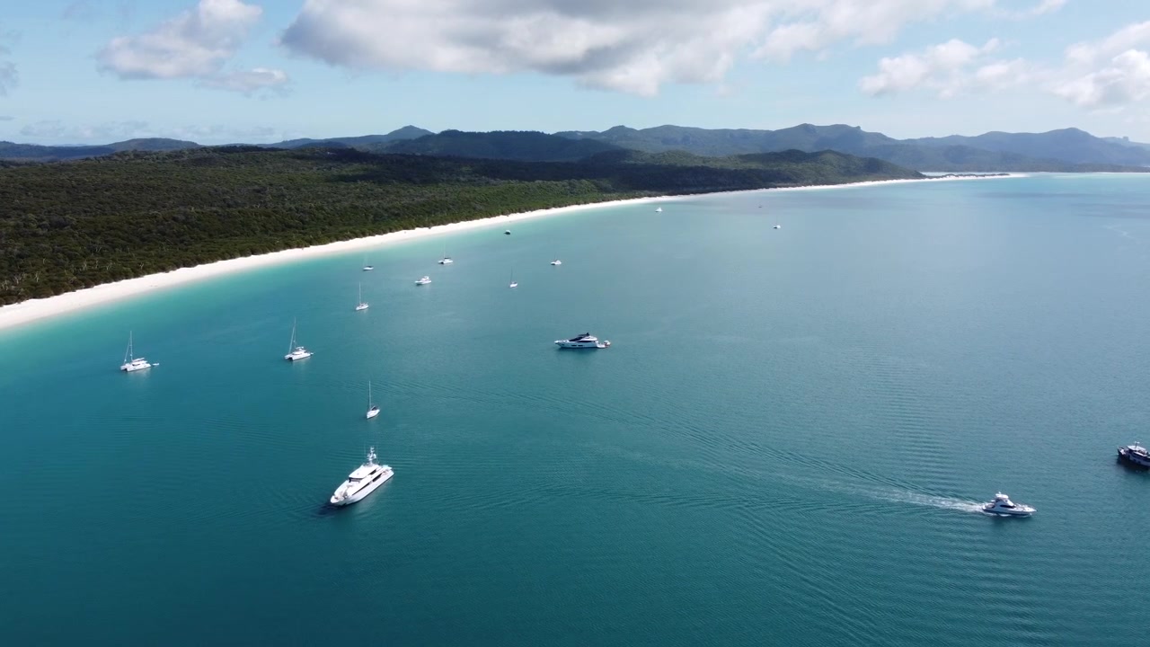 Ampia veduta aerea della famosa Whitehaven Beach che mostra barche e yacht ancorati nelle acque turchesi dell'oceano lungo la costa di silice bianca