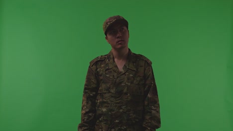 distressed asian male soldier looking around and shaking his head being sad due to the war while standing on the green screen background