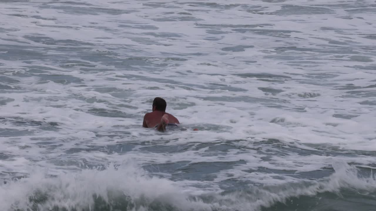 한 수영 선수 가 격동적 인 바다 파도 와 싸우고 있다