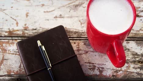 coffee mug and diary on wooden plank