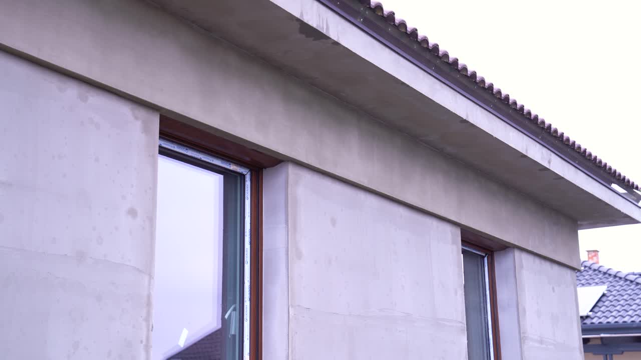 House facade with fresh cement plaster and newly installed modern window frames