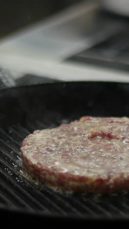 cooking a hamburger patty on a grill pan