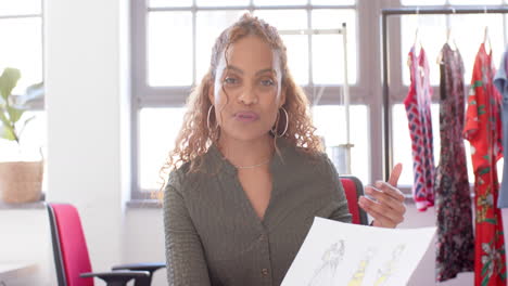 diseñadora de moda bi-racial feliz sosteniendo el proyecto y discutiendo en el estudio, cámara lenta