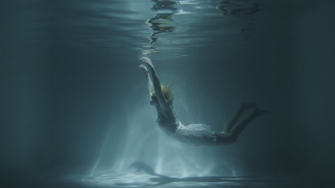 드레스를 입은 아름다운 소녀가 바닥으로 가라앉습니다.