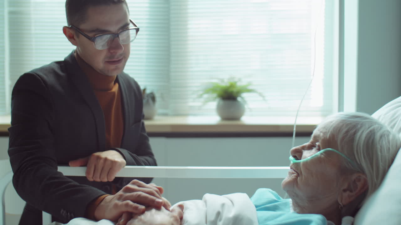 병원 병실 에서 노인 어머니 를 지원 하는 남자