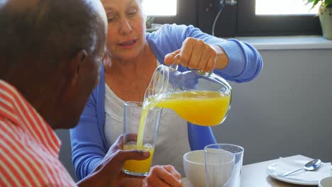 Senior-woman-pouring-juice-into-glass-to-her-friend-4k