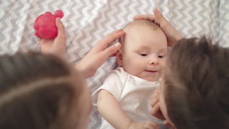 Wunderschönes-Babygesicht.-Nahaufnahme-Von-Geschwistern,-Die-Einen-Kleinen-Jungen-Berühren,-Der-Auf-Dem-Bett-Liegt