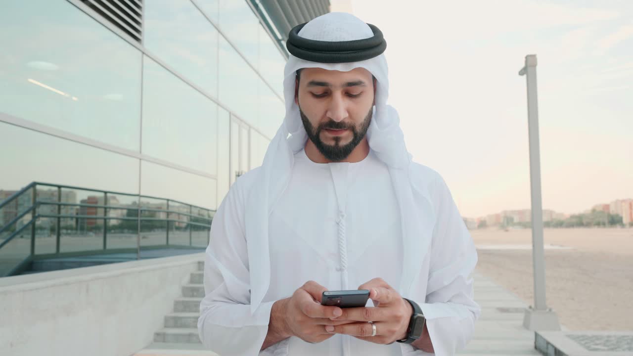 hombre emiratí de los emiratos árabes unidos usando un teléfono celular móvil