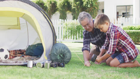 Feliz-Abuelo-Caucásico-Y-Nieto-Armando-Carpa-Juntos-En-El-Jardín,-Cámara-Lenta