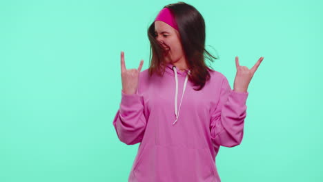 overjoyed teen girl showing rock n roll gesture by hands, cool sign, shouting yeah with crazy face