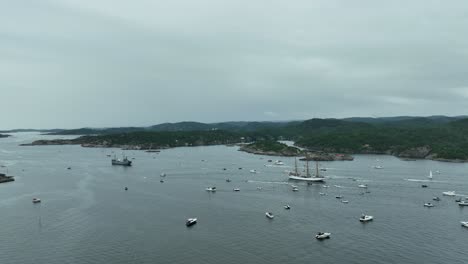 numerous boats are anchored in the tranquil waters of a coastal area, surrounded by lush hills under a cloudy sky just before evening. the scene evokes a peaceful maritime atmosphere