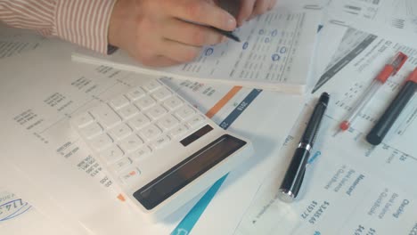 disparo de cerca de una mano masculina haciendo algunos cálculos y tomando notas en el informe financiero