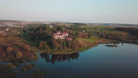 elevating pan drone shot of a castle next to a lake that reflects it