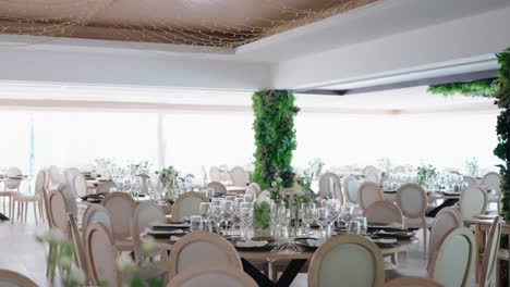 elegantly arranged reception space with round tables, soft lighting, and greenery accents on columns