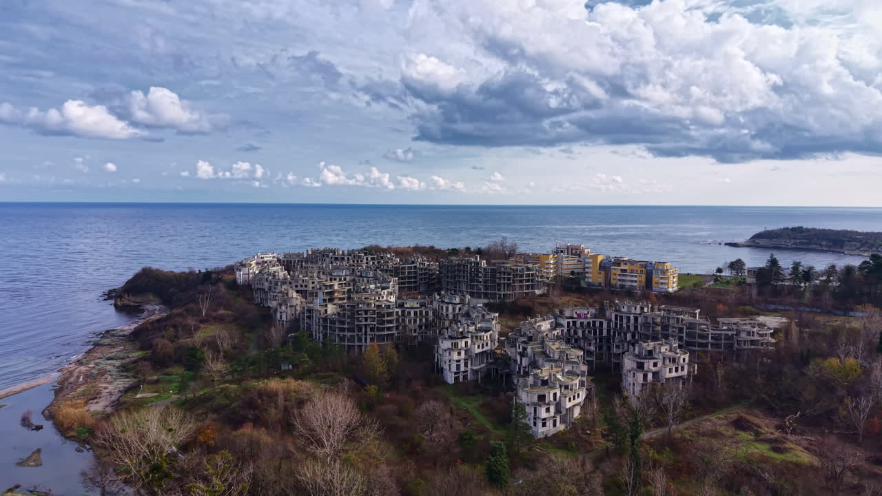 Abandoned coastal city emerges from nature's grasp, revealing the passage of time against a stunning seascape under dramatic skies