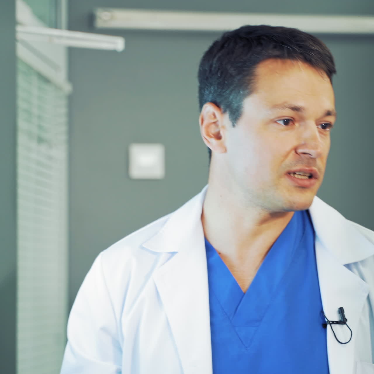 Portrait of a man doctor talking to someone. Medical worker in special uniform explaining his research while standing near the screen with x-rays photography indoors.