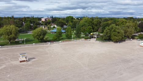 clean, empty white sand beach with lifeguard huts, boardwalk and treed park in tourist town