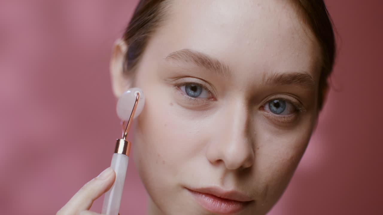 mujer usando un rodillo de jade para el masaje facial