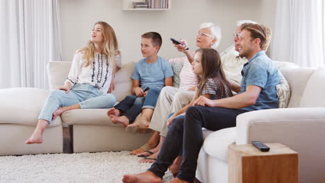 Familia-Multigeneracional-Sentada-En-El-Sofá-En-Casa-Viendo-La-Televisión