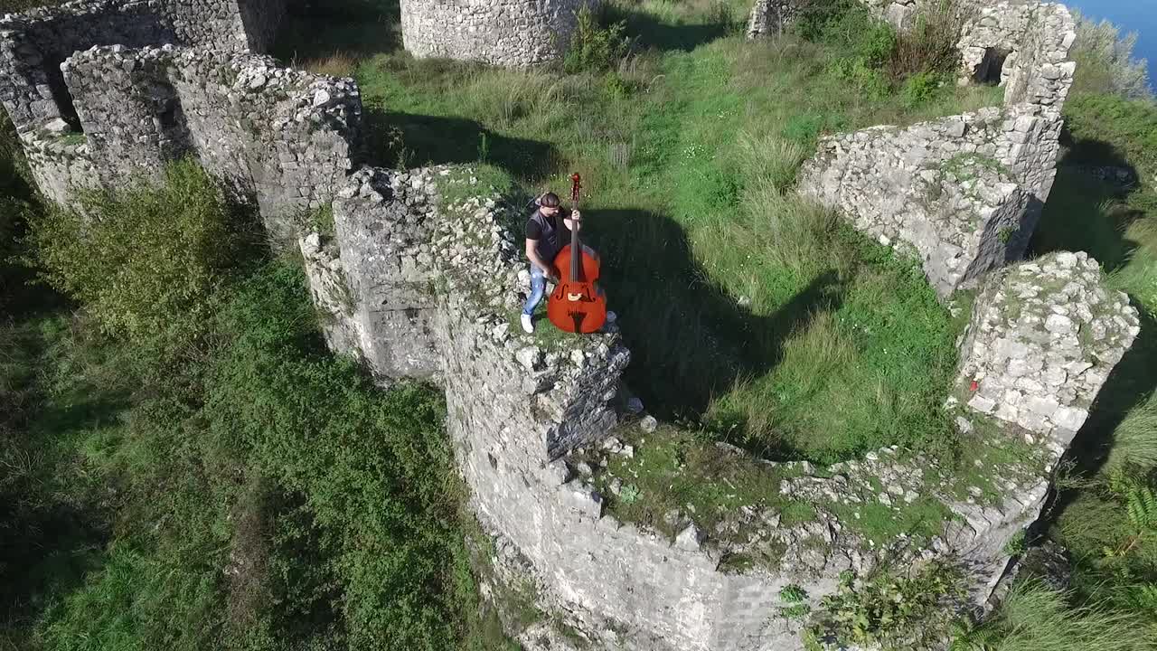 hombre tocando el bajo en las ruinas de una fortaleza