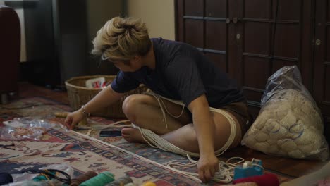 person untangling yarn or cord for a craft project on the floor