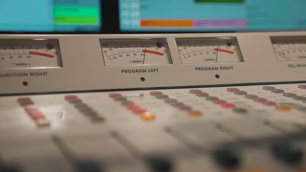 Radio audio board with peaking sound signals, buttons on mixing panel in studio