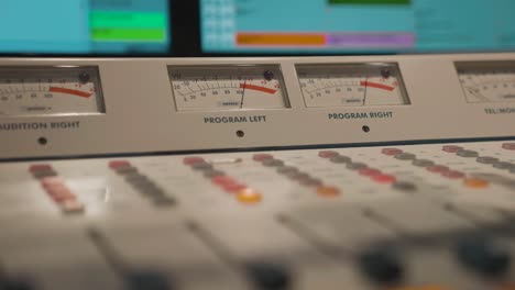 Radio audio board with peaking sound signals, buttons on mixing panel in studio