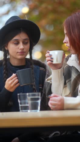 two women enjoying a coffee date outdoors in autumn