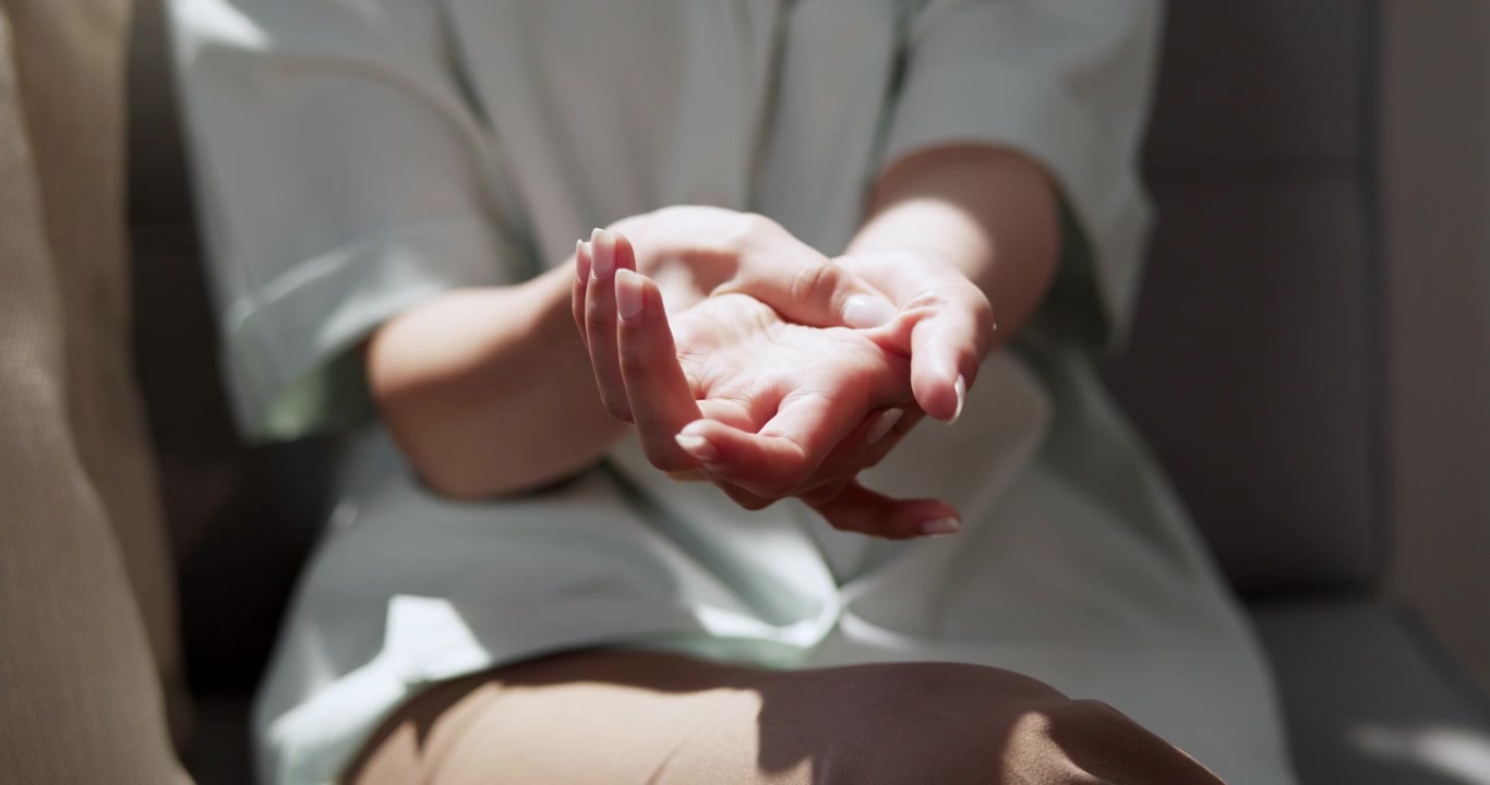 Un primo piano di mani che allungano le dita a casa mostra pratiche di benessere per il relax e il sollievo dallo stress