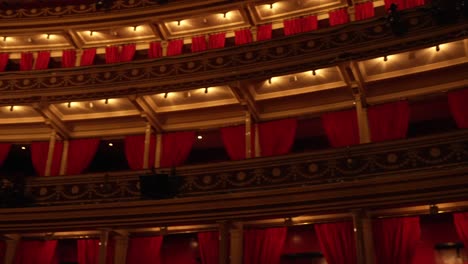 Empty-balconies-of-a-stunning-venue,-red-velvet-seats-and-dimmed-lights-flashing,-in-London