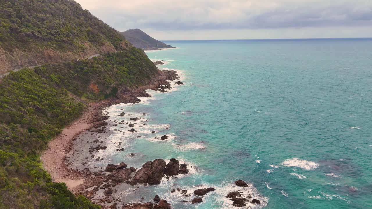 Drone captures the rugged coastline of Lorne, Victoria, with turquoise waters and lush greenery under soft daylight
