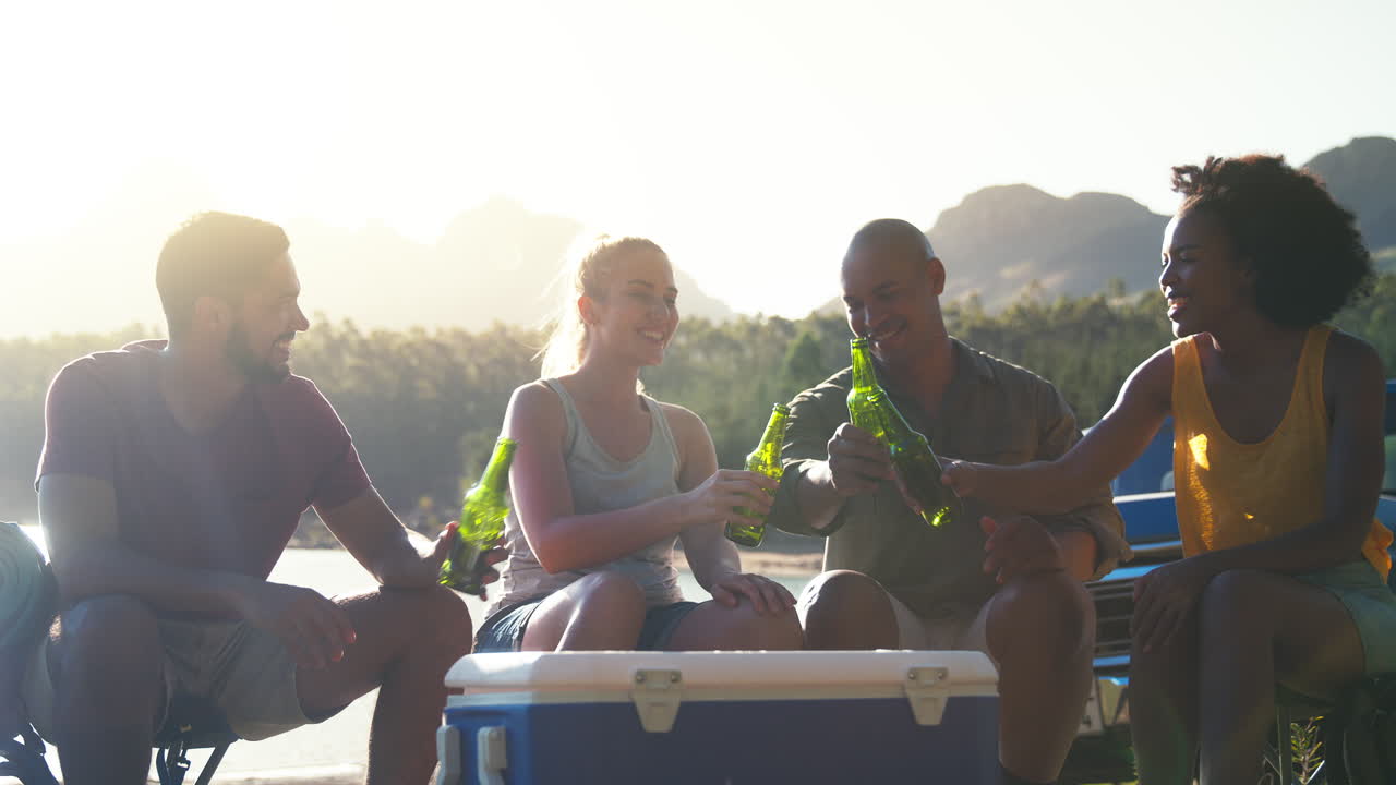 호수에서 냉장고에서 맥주를 마시는 도로 여행에 픽업 트럭으로 배을 가진 친구 그룹